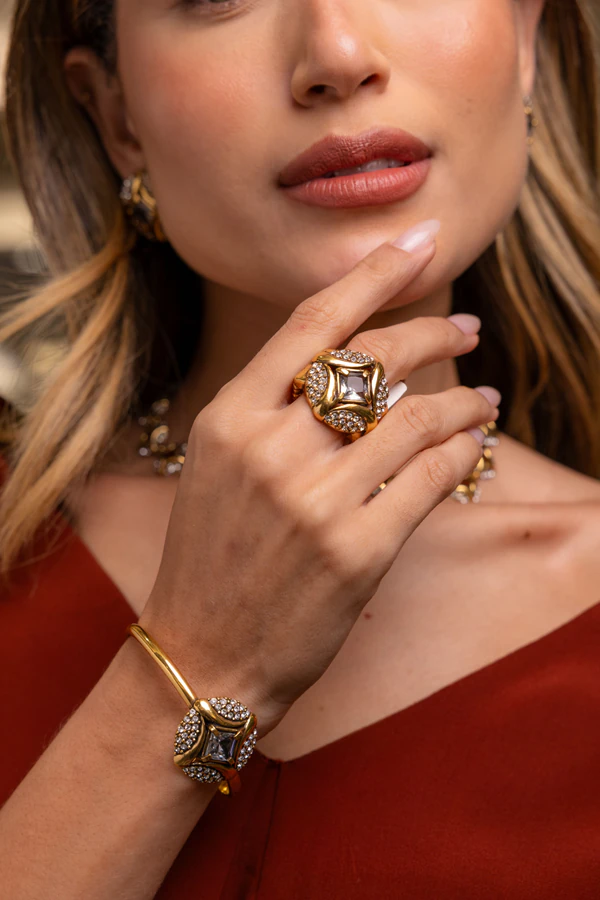 Fotografia de joias com anel e bracelete dourados usados por uma modelo.