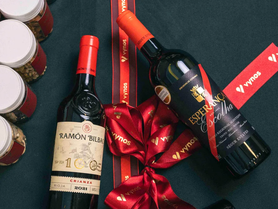 Composição de vinhos e fitas da Vynos sobre fundo escuro.