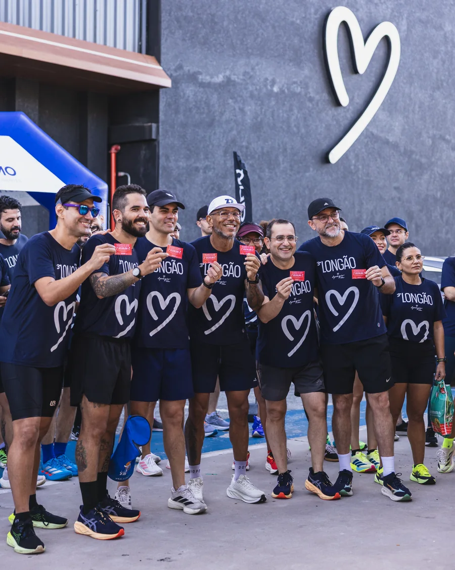 Grupo de pessoas com camisetas escuras posa diante da fachada do Spazio.